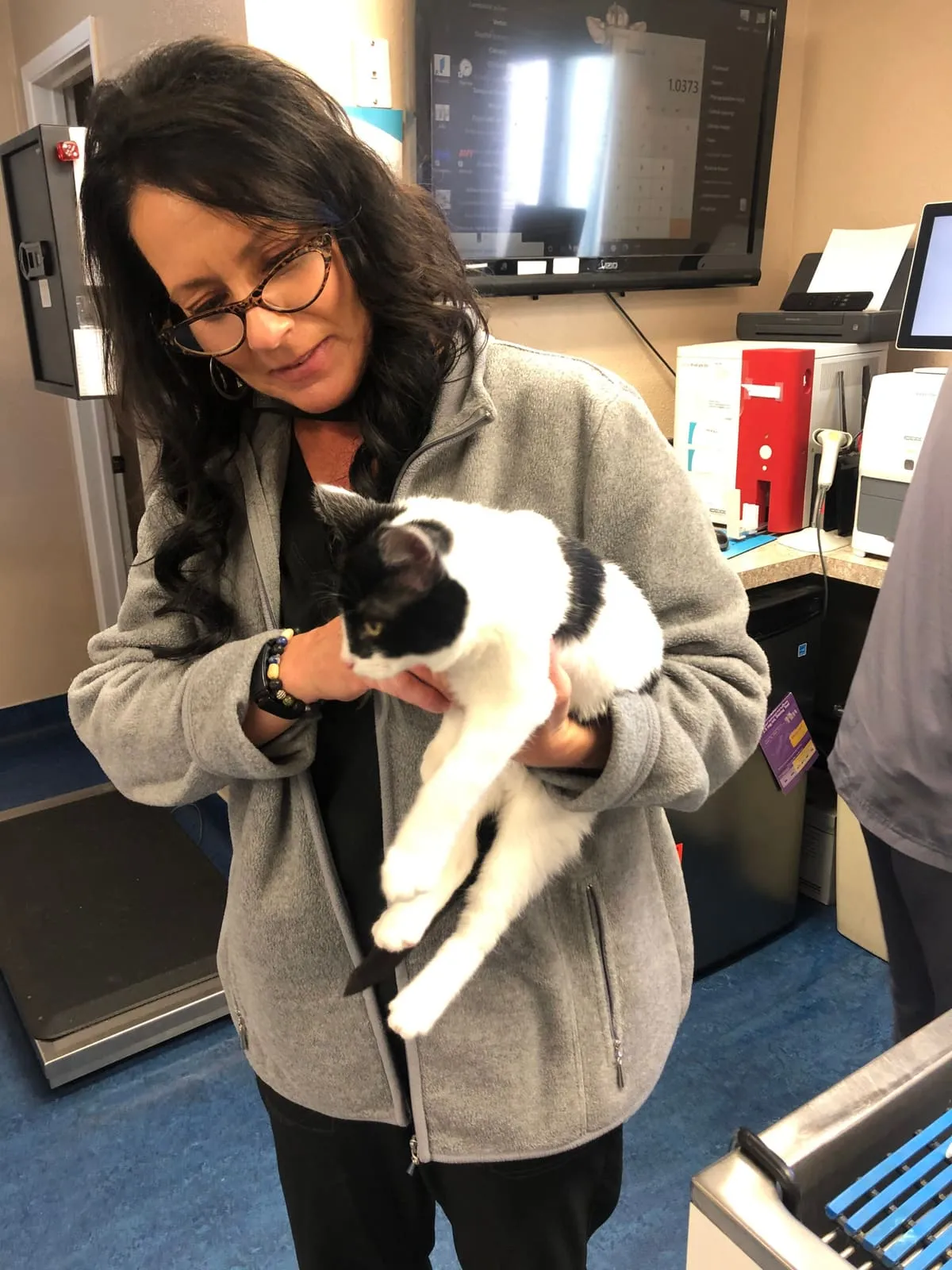 A woman holding a black and white cat at the hospital