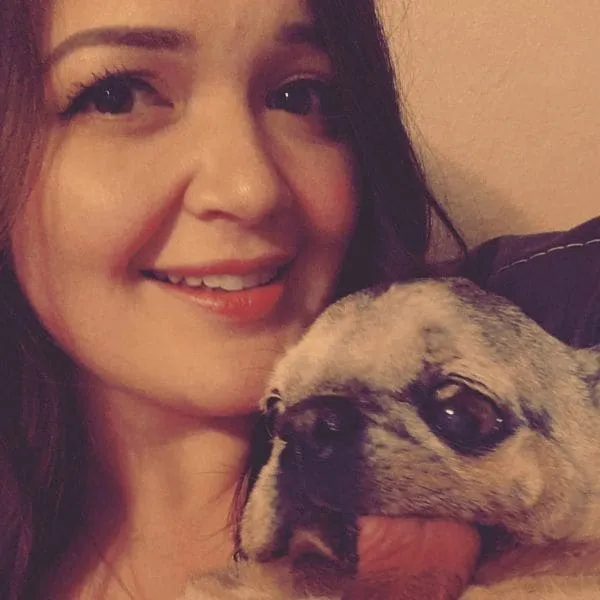 Team member Briana cheek to cheek with her pug