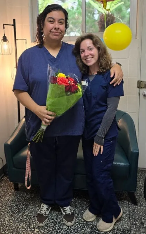 Two team members with flowers and balloons on Kasandra’s last day