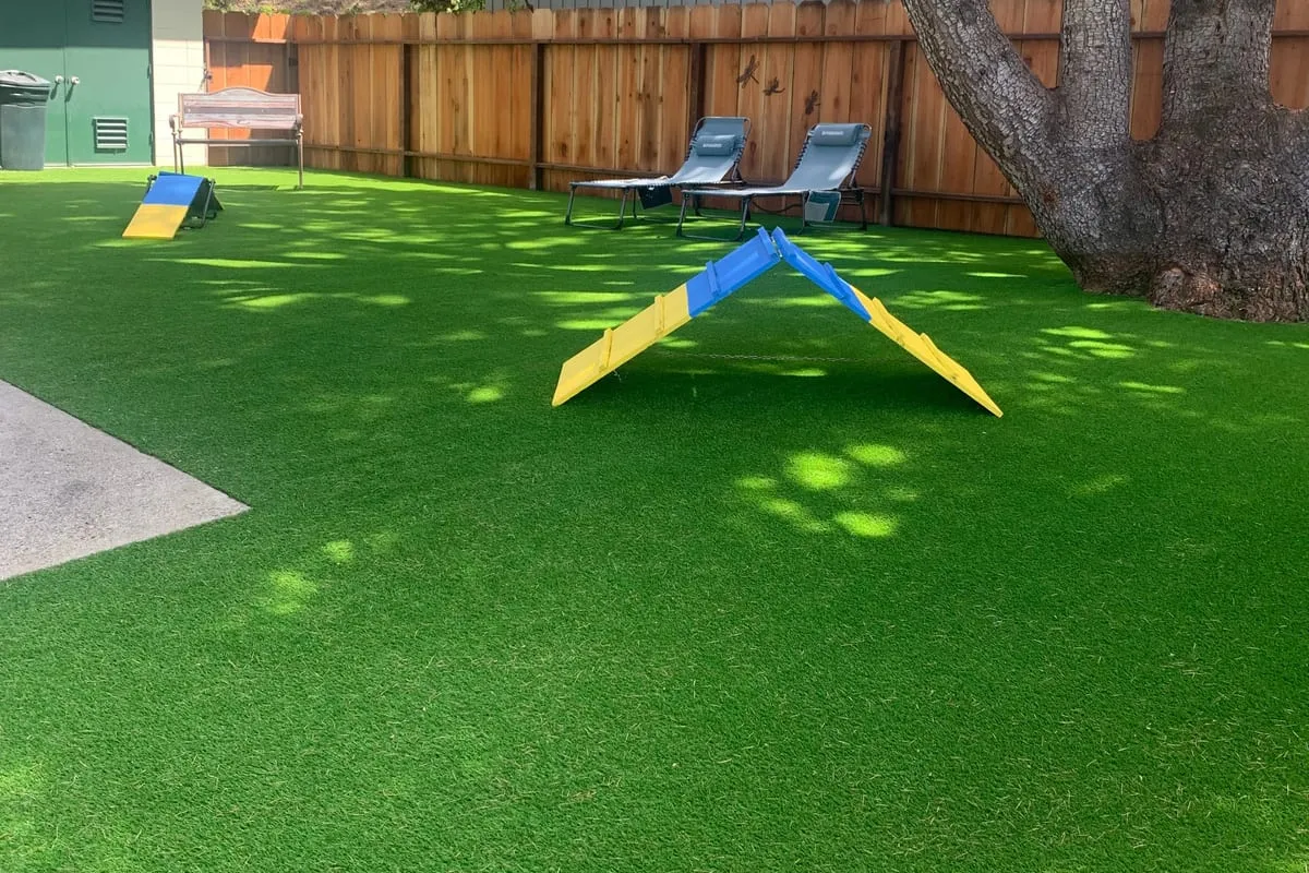 The hospital's secured outdoor play yard with artificial turf and agility ramps