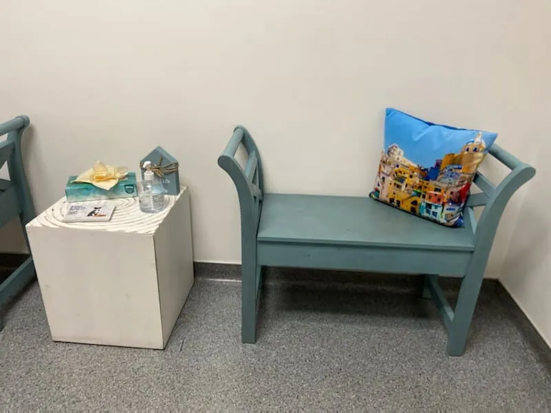 A bench with a colorful pillow in the waiting area